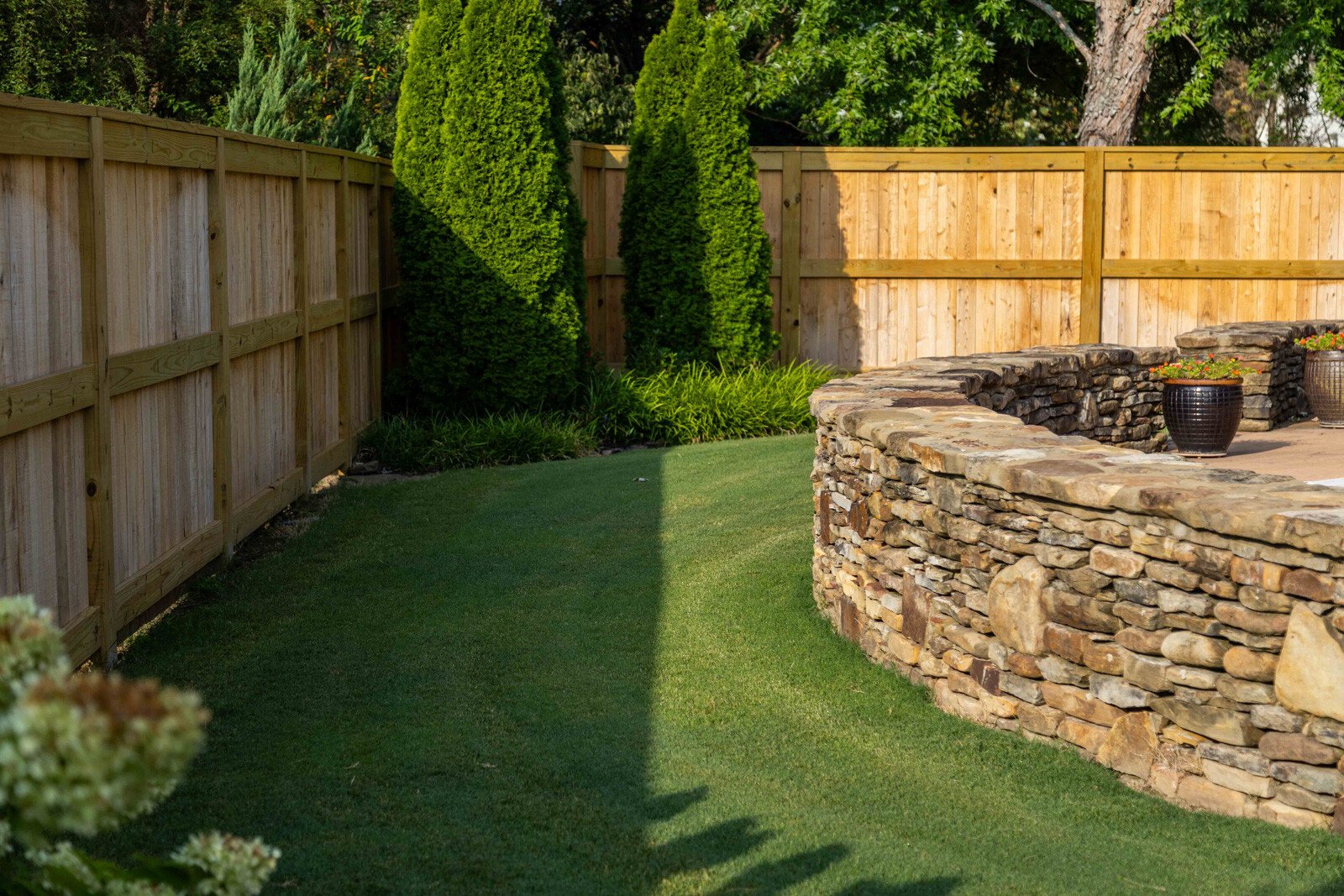 turf lawn stone wall fence shrubs