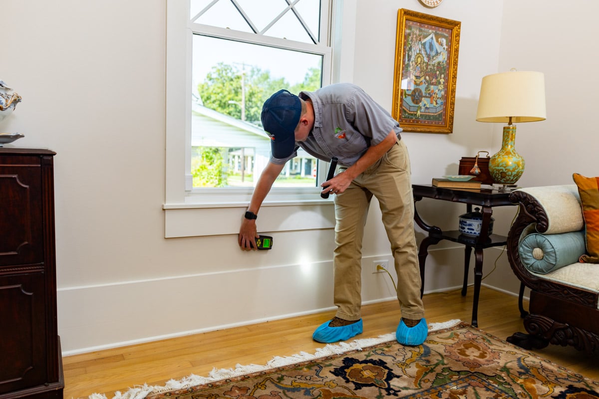 pest control technician inside a home with moisture meter to inspect for termites
