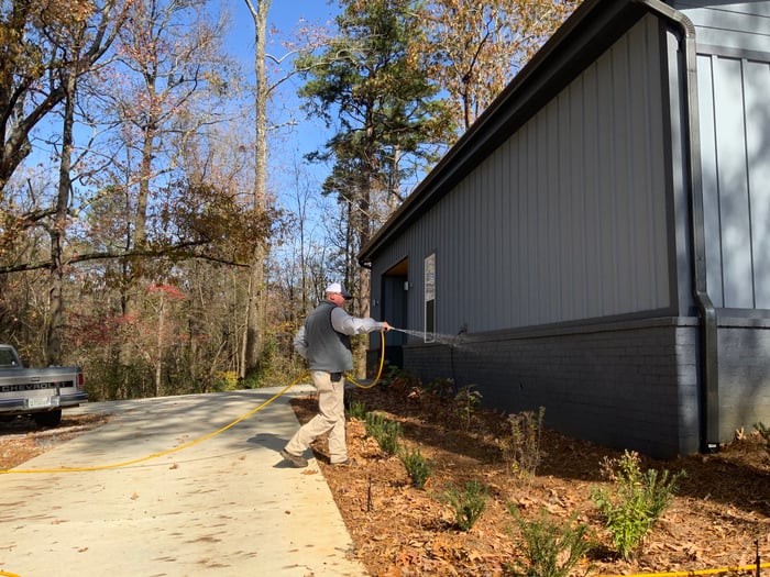 pest control technician spraying perimeter of house outdoor pests (2)