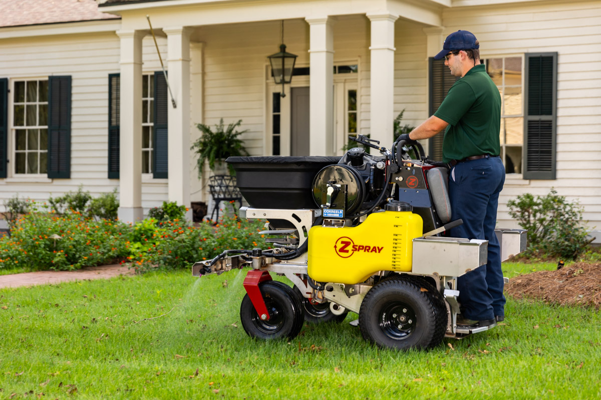 lawn care technician running a granular spreader on a nice memphis front yard