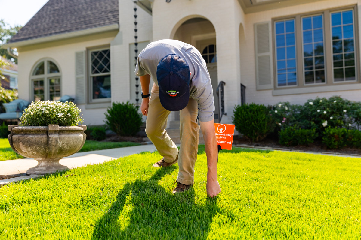 pest control technician placing yard sign in lawn